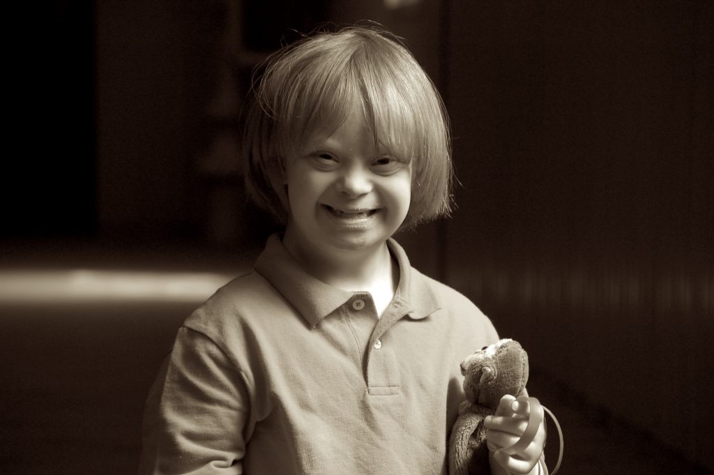 Photo of young child smiling and holding a stuffed animal