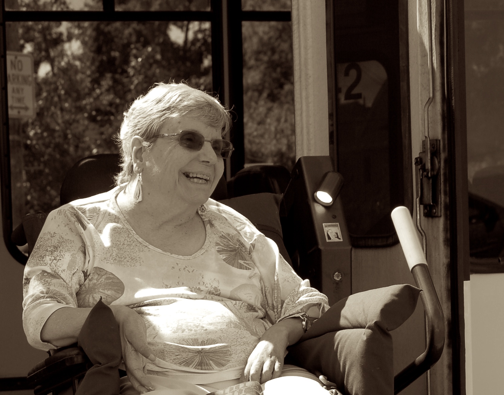 Photo of woman in wheelchair smiling and using the accessible lift on a bus to be independent